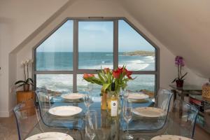 una sala da pranzo con tavolo e vista sull'oceano di Fistral beach Penthouse, Newquay a Crantock