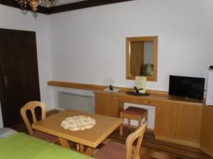 une salle à manger avec une table et une télévision dans l'établissement Gästehaus am Walde - Familie Troller, à Ledenitzen