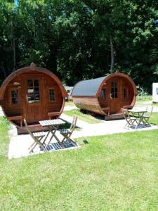 two large wooden lodges with a table and chairs in the grass at Campingplatz Aichelberg in Aichelberg