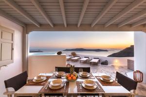 a dining room with a table and a view of the ocean at 180° Caldera by Stylish Stays in Firostefani +32 photos