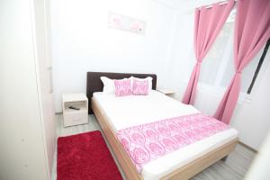 a bedroom with a bed with pink curtains and a red rug at Apartament Nacis in Mamaia Sat/Năvodari