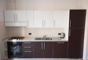 a kitchen with white cabinets and a black refrigerator at Castel View Apartment - Gardaslowemotion in Tenno