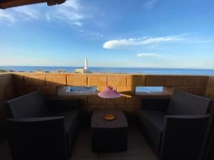 uma varanda com uma mesa e cadeiras e o oceano em Sicilian Seaside Apartments em Augusta