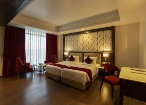a hotel room with a large bed and a desk at Sarovar Portico, Somnath in Somnath