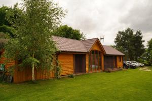 eine Holzhütte mit einem Rasenplatz davor in der Unterkunft Agroturystyka Witoldówka in Perlejewo