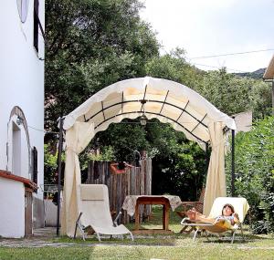 a woman sitting in a chair under a tent at Villa il Poderino in Marina di Campo
