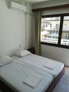 uma cama num quarto com uma grande janela em White Coral em Paralia Katerinis
