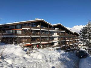 un bâtiment dans la neige avec une voiture garée devant dans l'établissement Apartment Axams, à Innsbruck