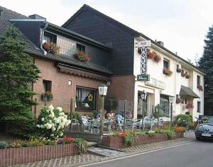 um restaurante com mesas e cadeiras em frente a um edifício em Hotel Haus Gertrud em Simmerath
