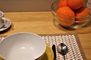 Cardeal Suites & Apartments في فارو: طاولة مع وعاء من البرتقال وصحن وملعقة