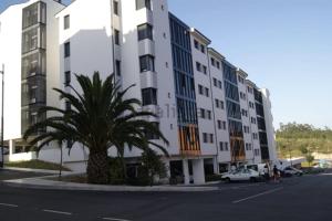 un edificio con una palmera frente a una calle en Area Suites, en Jove (Xove)