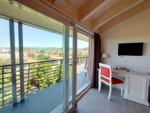 a room with a balcony with a desk and a television at Nuova Opera Rooms & Apartments in Verona