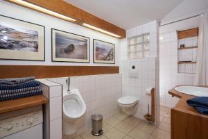 ein Badezimmer mit einem WC, einem Waschbecken und einem Urinal in der Unterkunft Heuboden in Mellenthin