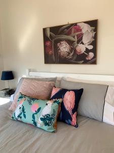 uma cama com duas almofadas e um quadro na parede em La Dolce Vita em Beechmont