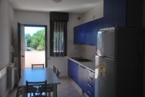 a kitchen with blue cabinets and a table and a refrigerator at Acquasmeralda appartamento 01 in Rosolina Mare