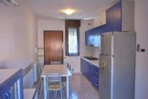 cocina con nevera, mesa y sillas en Acquasmeralda appartamento 01 en Rosolina Mare