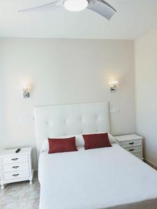 um quarto com uma cama branca e uma almofada vermelha em Hotel costa mar em Sanxenxo