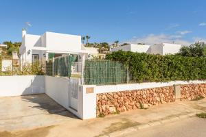 Casa blanca con valla y pared de piedra en Villa Cal Peixito, en Son Bou