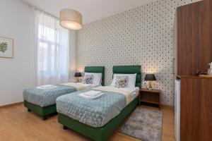 a bedroom with two beds with greenitures and a wall at Aurora Rooms B&B Pula in Pula