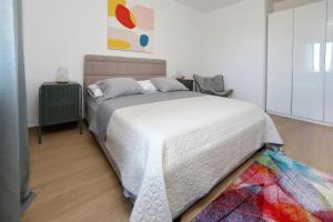 a bedroom with a large white bed with a colorful blanket at Apartmani Marta in Sukošan