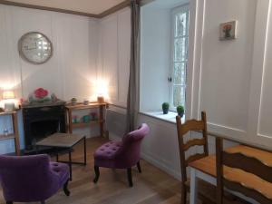 sala de estar con sillas moradas, mesa y reloj en Les Cottages du Château du Rozel, en Le Rozel