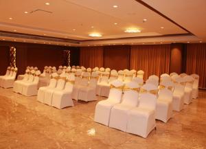a room with rows of white chairs and tables at Sarovar Portico, Somnath in Somnath
