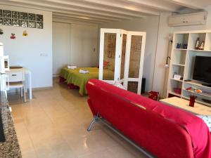 een woonkamer met een rode bank en een televisie bij Estudio Lala conil in Conil de la Frontera