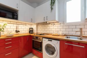 a kitchen with red cabinets and a washing machine at Casa Cosi - Sants in Barcelona