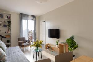 a white living room with a tv and a couch at Casa Cosi - Sants in Barcelona