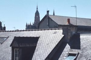 a roof of a building with a clock tower in the background at La maison perchée in Bayeux +3 photos