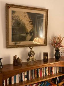 uma foto na parede acima de uma estante de livros com livros em Poppys Chambres d'Hotes em Céret