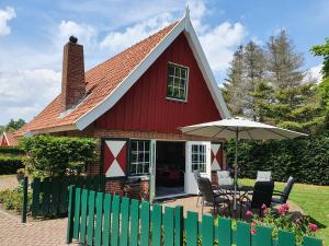 a red house with a table and an umbrella at Lekker Plekje Achterhoek in Lievelde