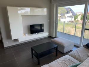 a living room with a couch and a table and a tv at Karthuizer appartement in Nieuwpoort