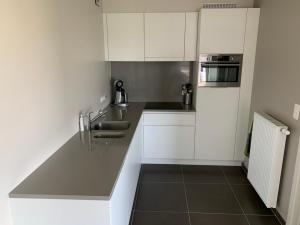 a kitchen with white cabinets and a counter top at Karthuizer appartement in Nieuwpoort
