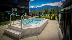 uma banheira de hidromassagem num pátio com montanhas ao fundo em Stoke Hotel SureStay Collection by Best Western em Revelstoke