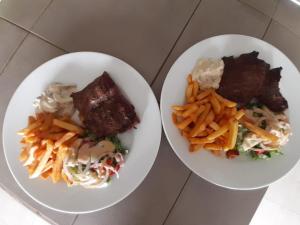 dois pratos brancos de comida numa mesa em Hotel le Trarza em Niaga