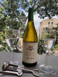 a bottle of wine and two glasses on a table at huge apartment near to Bahai Garden in Haifa