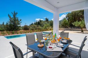 a table and chairs on a patio with a pool at Diosas Luxury Villas in Pilaroú