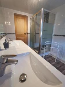 y baño blanco con lavabo y ducha. en Gîte des biches, en Birkenwald