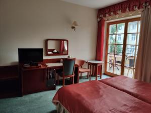 a hotel room with a bed and a desk and a window at Willa Pod Dębami in Świnoujście