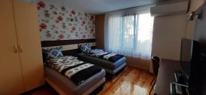 een kleine kamer met 2 bedden en een raam bij Апартамент ГЕТО - 2 Комфорт in Belogradchik