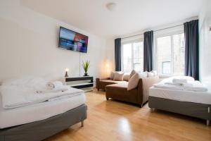 a bedroom with two beds and a chair and a couch at Old Town 2 Room Apartments in Düsseldorf