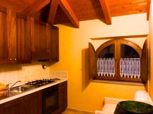 cocina con armarios de madera, fregadero y ventana en Villa Nigro, en Laureana Cilento