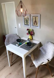 einen weißen Tisch und einen Stuhl mit einer Blumenvase in der Unterkunft Paradiesje in Leer