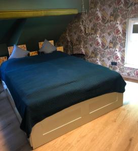 a bed with a blue comforter in a bedroom at Paradiesje in Leer