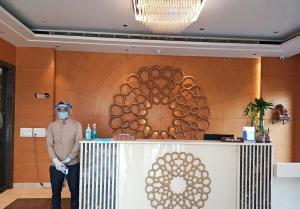 a man wearing a mask stands in front of a reception desk at Maple Grand in Agra