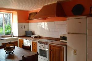 een keuken met oranje muren en een witte koelkast bij Casa "A Rúa" - Preciosa casa en la montaña con amplio jardín in Vilariño