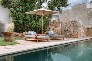 a patio with two chairs and an umbrella next to a pool at Paragon 700 Boutique Hotel & SPA in Ostuni