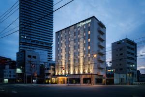 a building in a city with two tall buildings at Nest Hotel Hiroshima Ekimae in Hiroshima