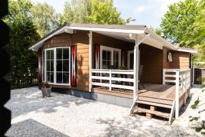a small cabin with a porch and a deck at Chalet aan de kust in Sint Maartensvlotbrug